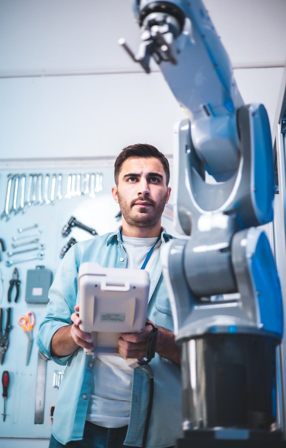 Entwickler mit Bedienpanel vor einem Roboterarm